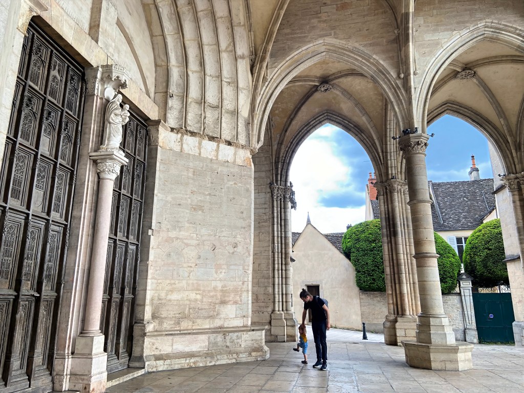 Father and toddler standing under the Basilique Notre Dame de Beaune in Beaune, France
