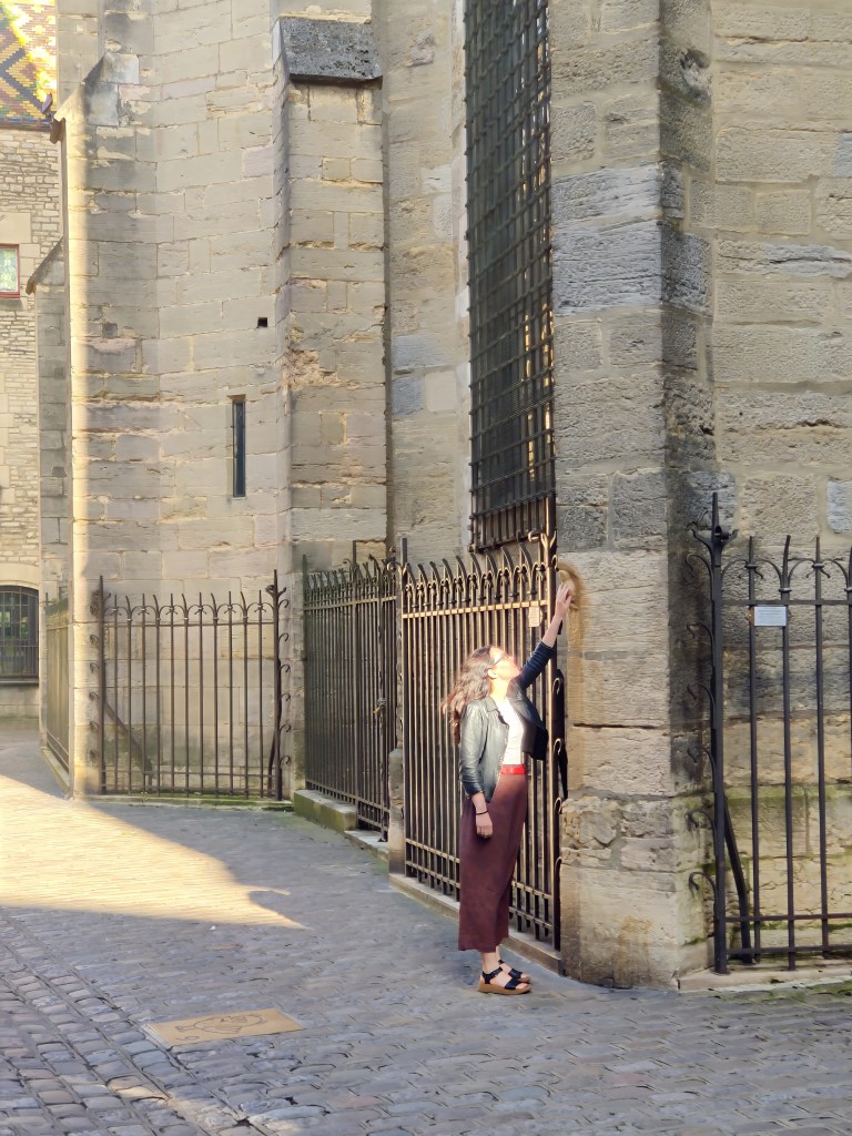 Woman touching the owl's face to make a wish at Notre Dame cathedral in Dijon, France
