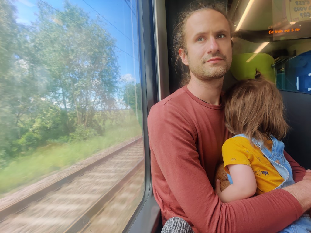 Father holding a tired toddler on a train ride in Beaune, France